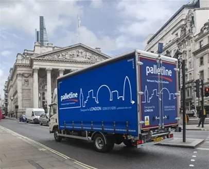 A Palletline truck driving through the City of London, passing by the Royal Exchange, with modern and classical architecture in the scene.