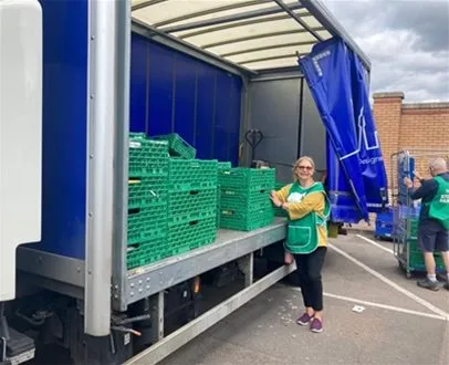 Volunteers unloading green crates from a logistics truck — showcasing last-mile delivery, warehousing support for food distribution, and community logistics